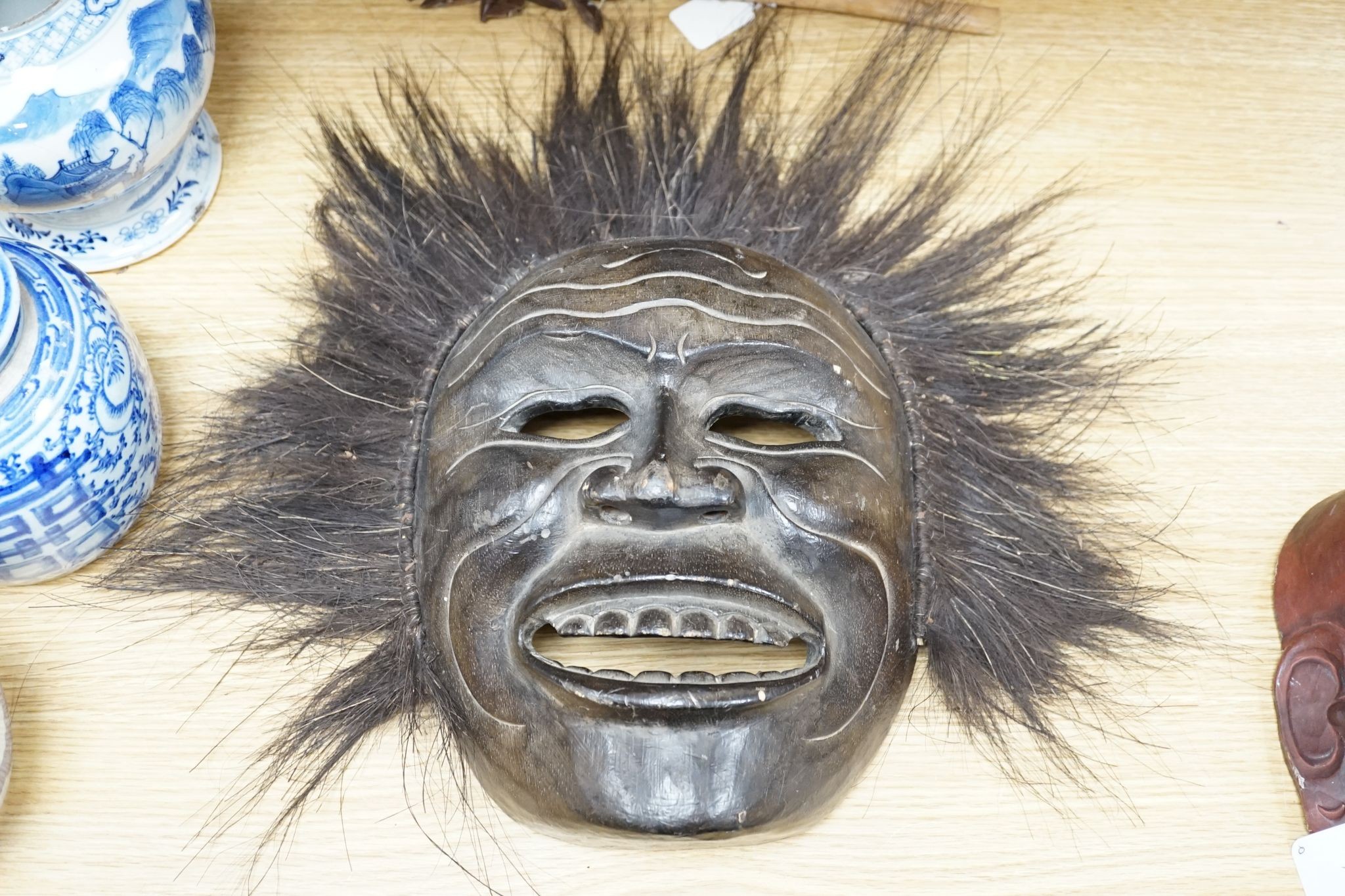 Two Japanese carved wood masks, an African beaded mask and three similar rattles